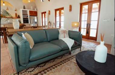 Living dining area with teal sofa, wood dining table, open plan at Casa Serena Pedasí Panama