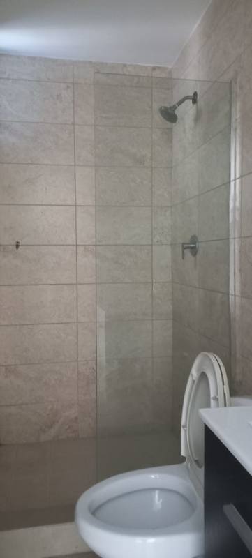 Bathroom with beige stone tiles, glass shower enclosure and sink vanity at PH Coral Towers Carrasquilla Panama