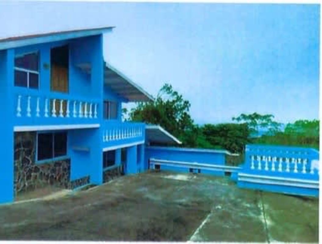 Blue painted guest house with porch and mountain greenery in Panama