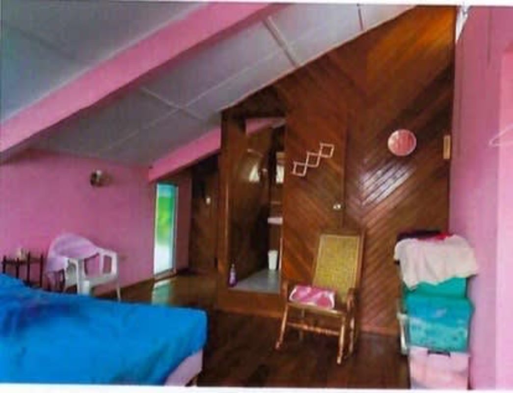 Rustic bedroom pink walls wood accents attic ceiling in mountain house Panama