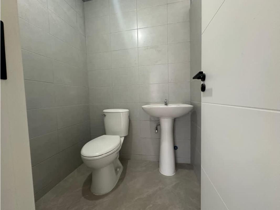 Minimalist bathroom with pedestal sink, toilet and tiled walls inside commercial space San Francisco Business Plaza Panama