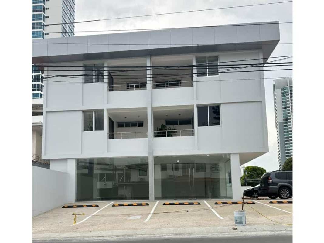 Commercial mixed-use building with glass storefronts, balconies, parking area visible from street San Francisco Panama City
