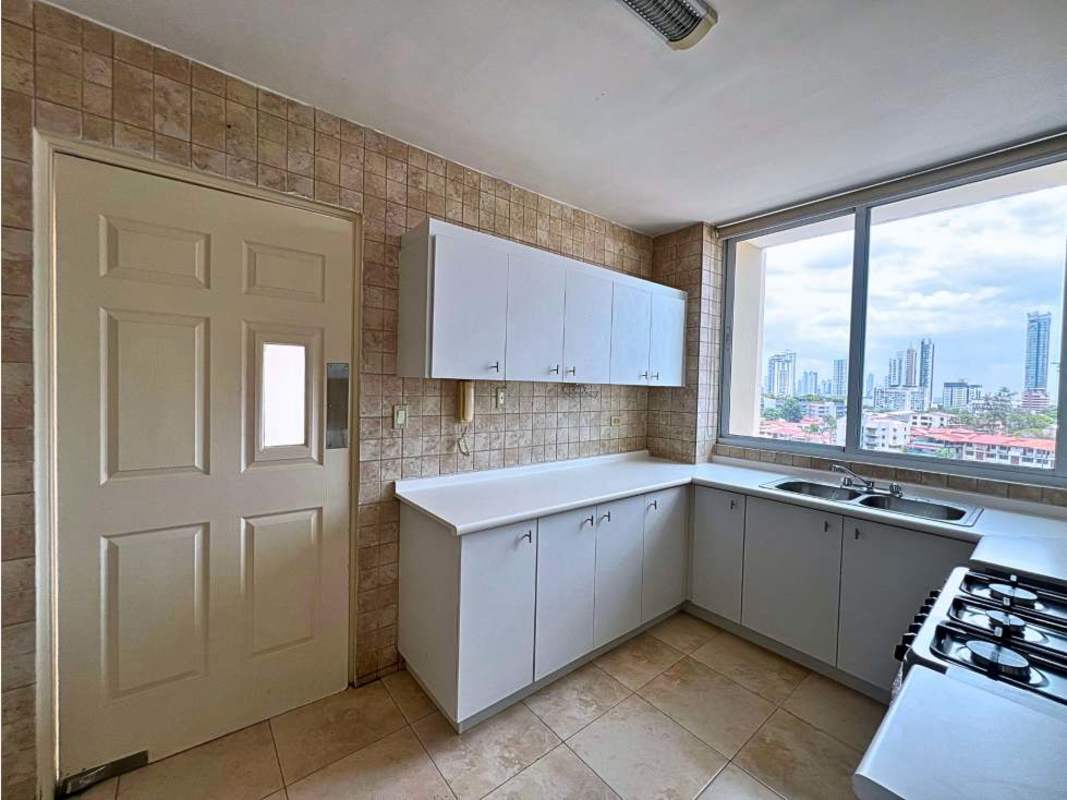 Modern kitchen with white cabinetry, double sink, stove and window with skyline view at PH Portofino Panama