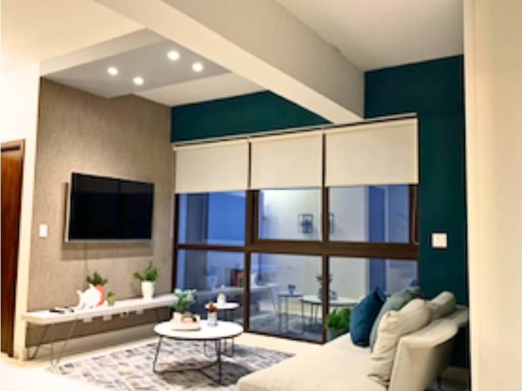 Living room with sectional sofa wall-mounted TV large windows plants at Mareas Beach Club Coronado Panama