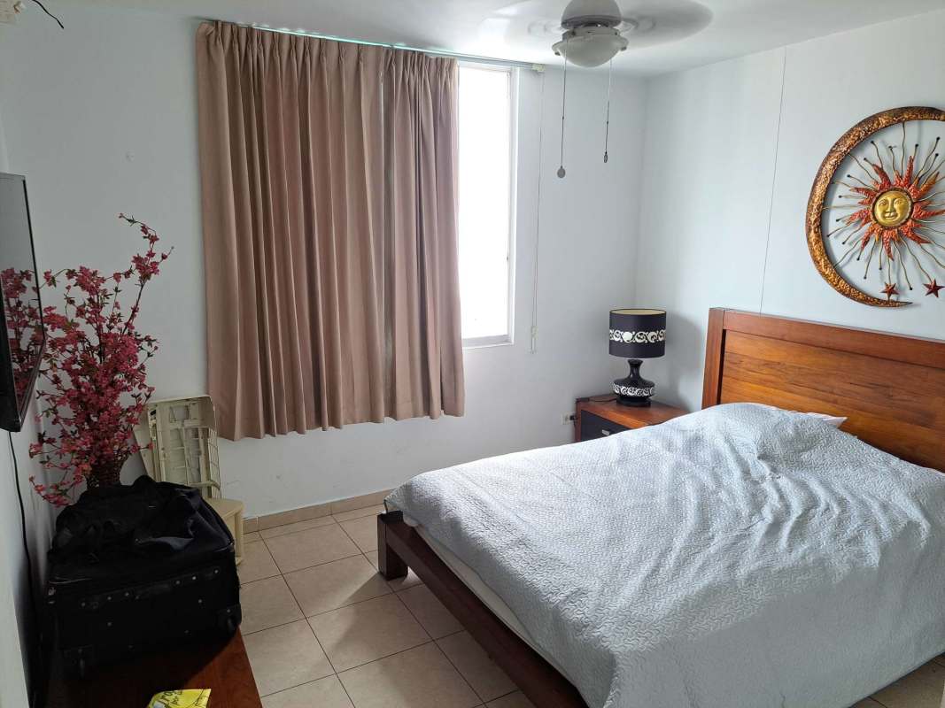 Bedroom with wooden bed frame, ceiling fan, wall art, in PH El Cangrejo Tower Panama City