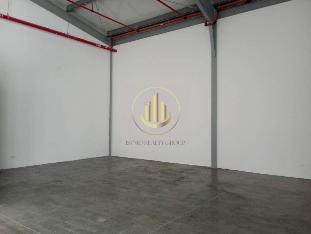 Utility room with exposed plumbing, white walls and concrete floor in commercial warehouse