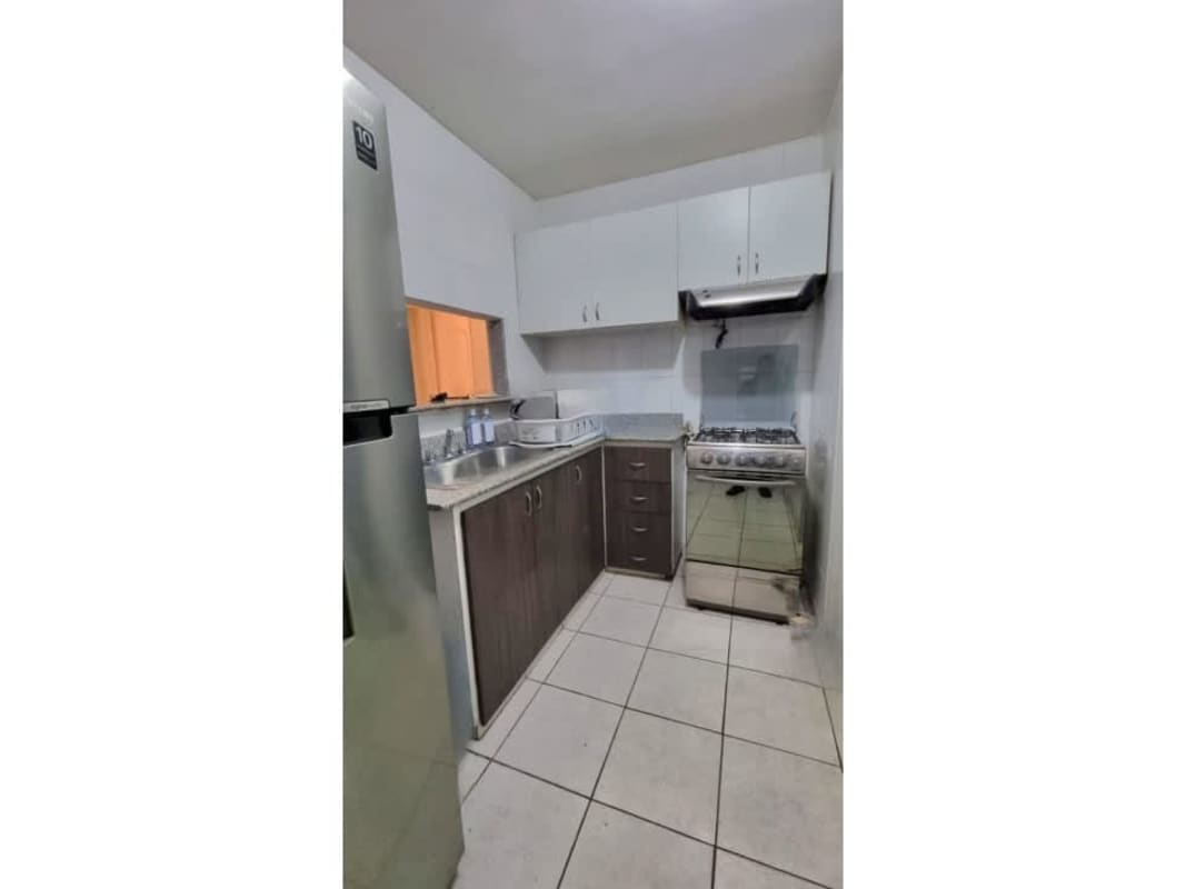 Compact kitchen with white cabinets, gas range, and double sink in PH Torres de Milán Panama City