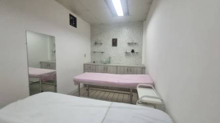 Minimalistic treatment room massage tables mirror cabinetry tiled backsplash in spa salon Panama Oeste