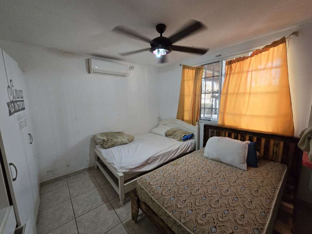 Spacious bedroom with two beds, AC, bright windows, tiled floors in Brisas del Golf house Panama
