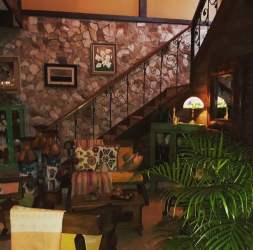 Mediterranean entrance with wooden doors, floral wreaths, colorful potted flowers in artisan house Penonomé Panama