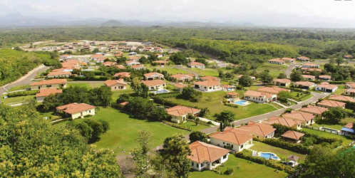 Aerial view of Hacienda Pacifica residential community with red tile roofs, pools, lush tropical landscape San Carlos Panama