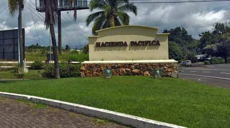 Entrance sign and landscaped lawn with palm trees Hacienda Pacifica residential development San Carlos Panama