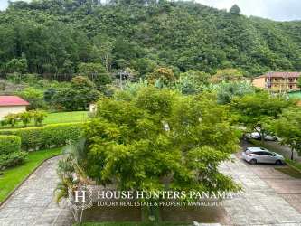 Lush green landscape with parking lot and mountain backdrop at PH Valle del Río Boquete