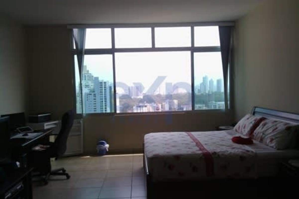 Bedroom with bed, workstation, large window overlooking city skyline Panama