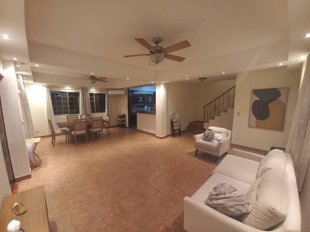 Spacious living and dining room with tile floor, ceiling fans, and staircase in Albrook Panama house