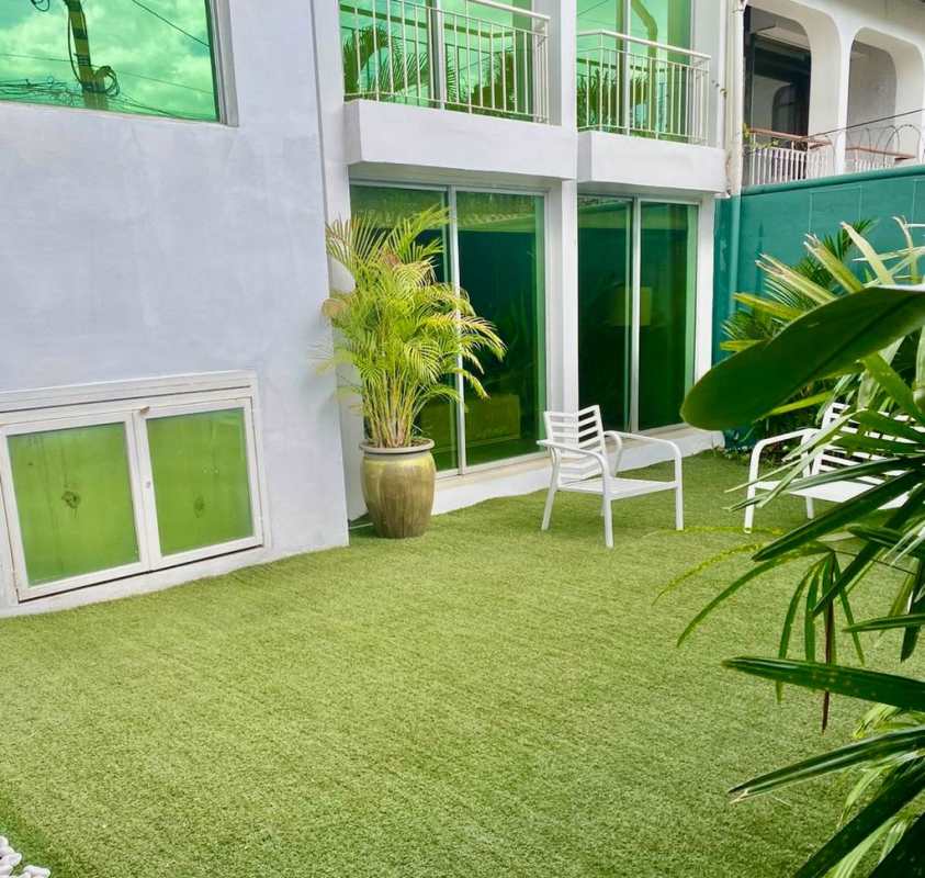 Backyard with artificial grass, white chairs, plants and privacy wall in La Alameda Panama City
