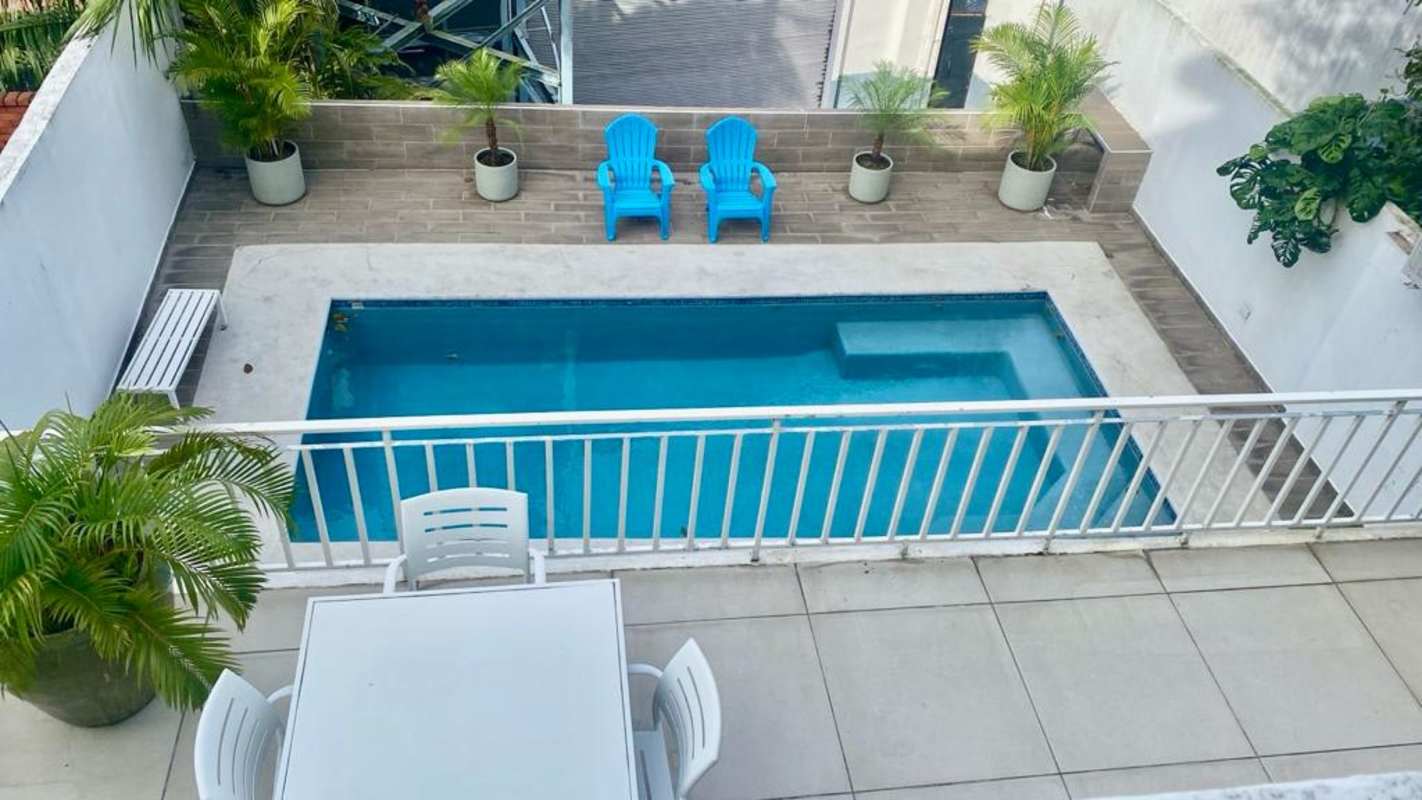 Backyard with swimming pool, blue chairs, white dining set and plants La Alameda Villa de las Fuentes Panama