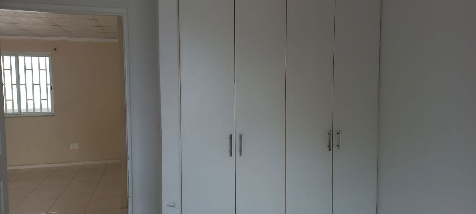 Bedroom with built-in wardrobe neutral tile floors window PH Ambar Pedregal Panama City