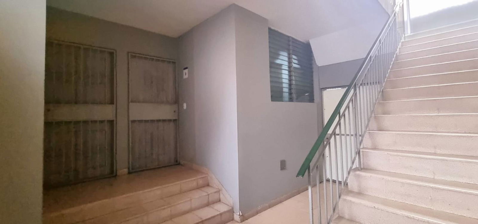 Interior common hallway with metal doors staircase and natural light in apartment building El Cangrejo Panama City