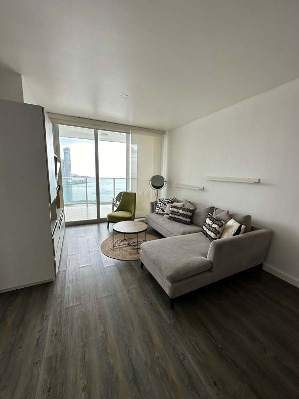 Configured living and dining room with balcony access, ocean view, elegant furniture at PH White Tower Panama