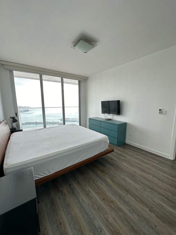 Bright bedroom with green dresser, oceanfront views, TV, wood floors at PH White Tower