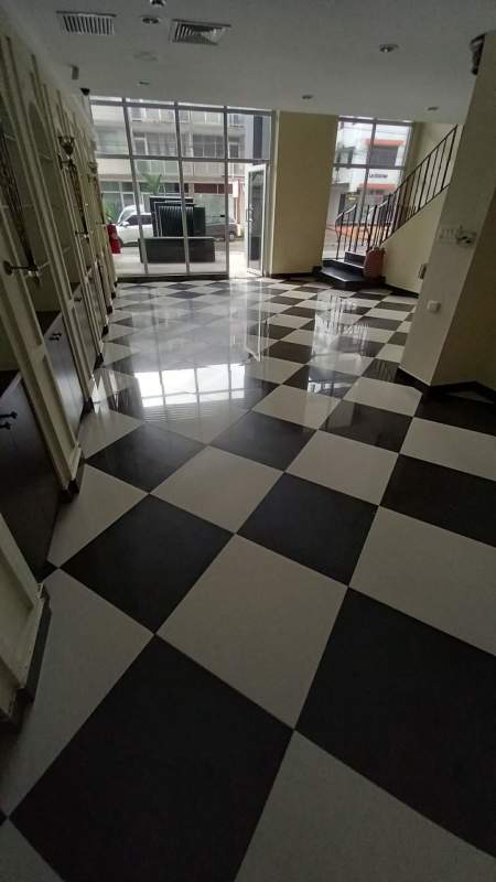 Lobby entrance hall with black and white checkered tile floor, large windows and staircase in Panama City commercial building