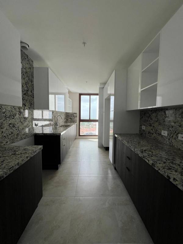 Modern galley kitchen with granite countertops, large window, and cabinets in The Colonial Santa Maria Panama