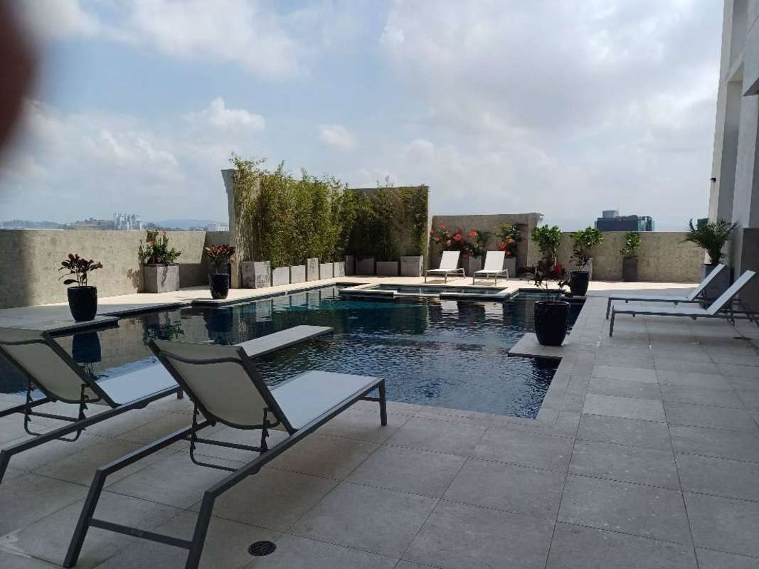 Infinity swimming pool with lounge chairs and city skyline view at The Colonial Santa Maria Panama