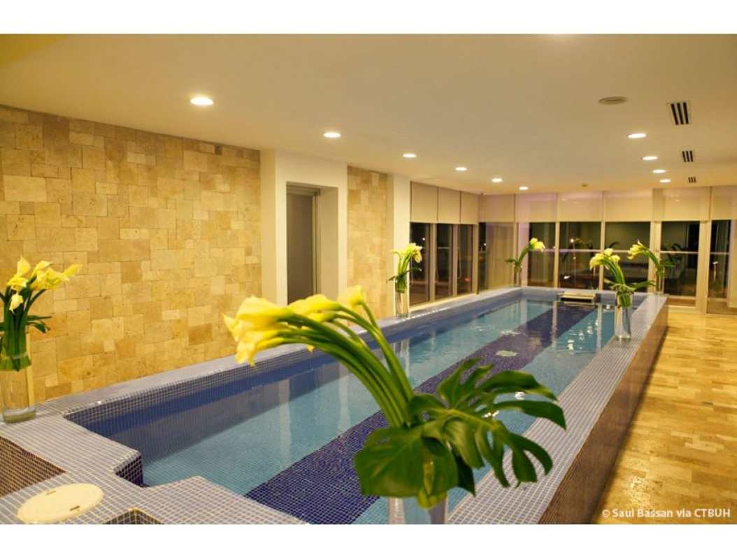 Long indoor lap pool with blue tiles and floor-to-ceiling windows at PH Rivage Avenida Balboa Panama City