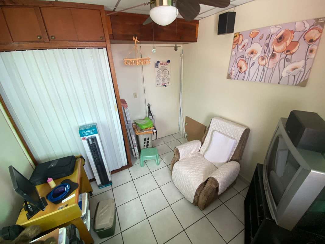 Interior room with desk, recliner, CRT TV, ceiling fan in affordable Panama apartment