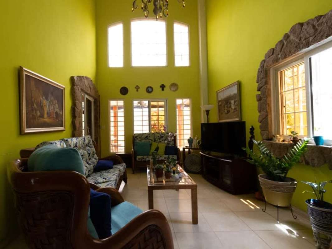 Living room double height ceiling, bright windows, lime accent wall, stone trim PH Rainforest Villas Panama City