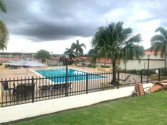 Outdoor community swimming pool with palm trees and umbrellas in Gran Reserva Montelimar Panama