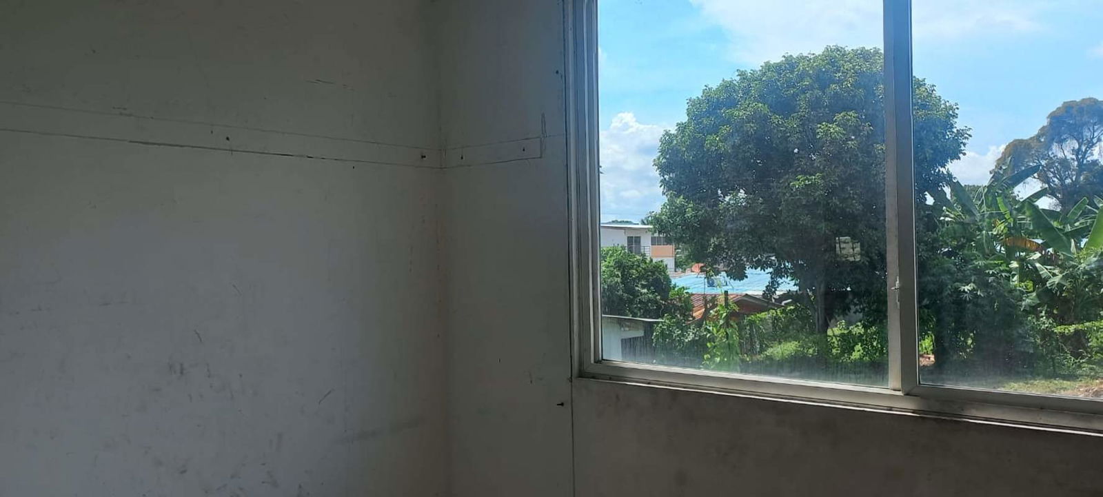 Large window with green landscape view inside bank repo apartment PH Vitto Pedregal Panama