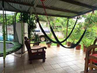 Covered outdoor patio with hammocks, plants, and large seating area La Chorrera