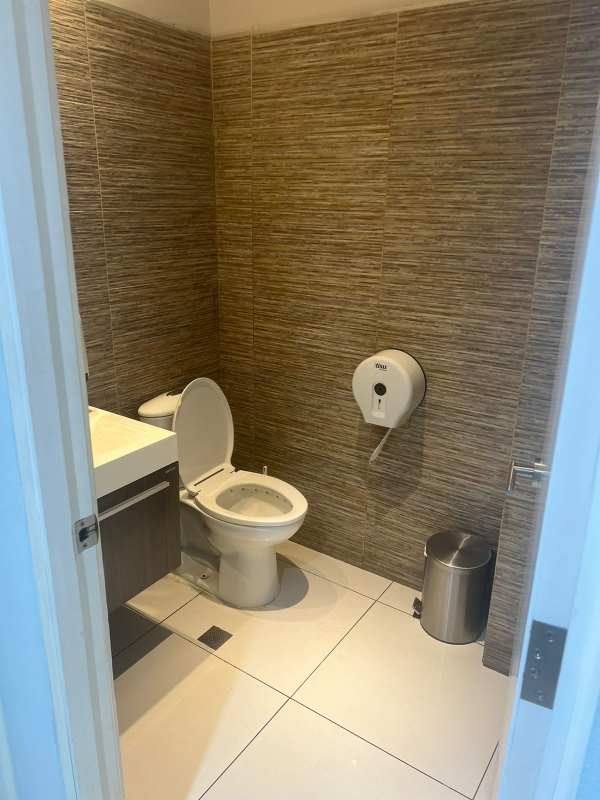 Small modern bathroom with brown tiles vanity toilet in commercial store Obarrio Panama