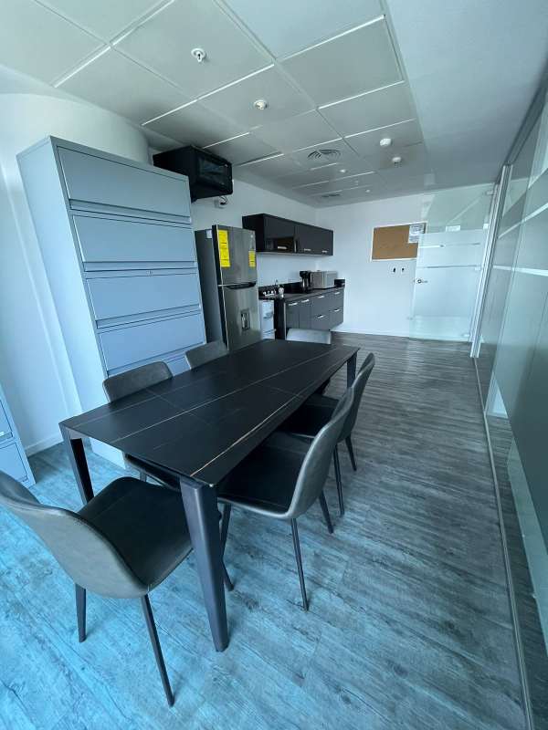 Office dining and kitchen space with fridge, microwave, and black cabinetry Punta Pacifica