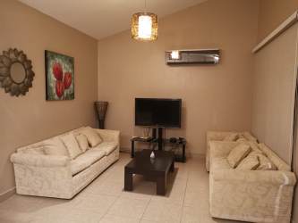 Spacious living area with ceiling fan, sofa, and TV at Las Guias Beach House Panama