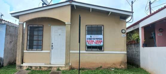 Front view of beige house with barred windows and 'For Sale' sign in Altos del Tecal
