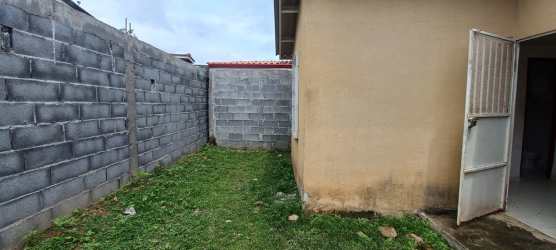 Side view with concrete wash basin and grass beside affordable Panama house