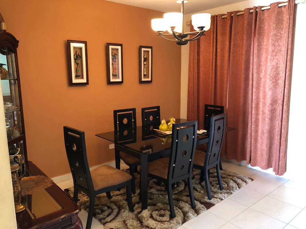 Dining room with glass dining table chandelier and paintings Costa Sur Panama