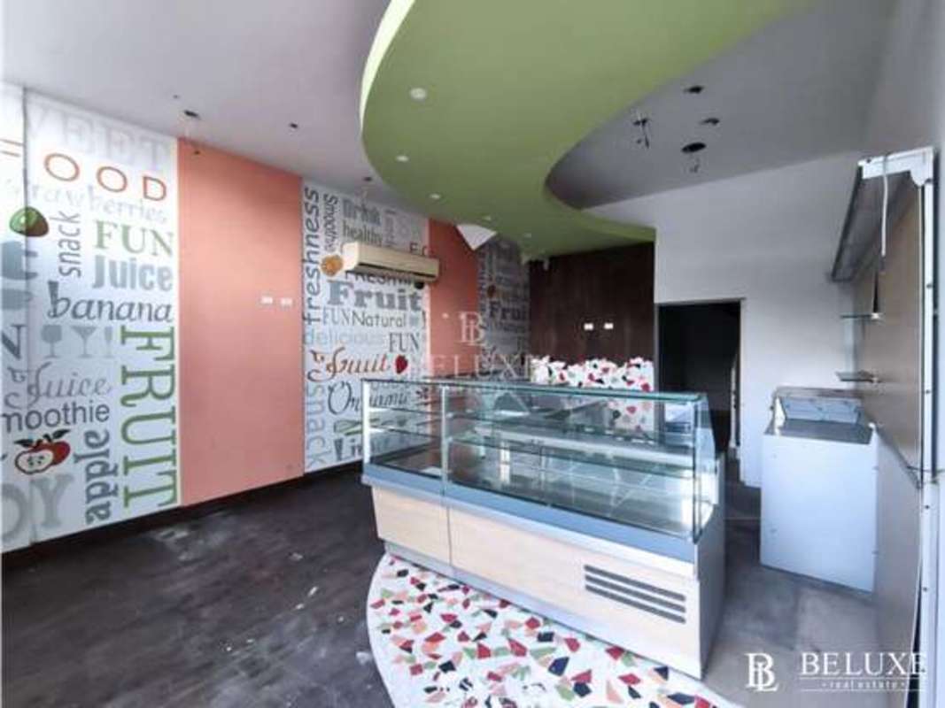Open commercial space with green accent ceiling, glass display counter and terrazzo floors Plaza 68 San Francisco Panama City