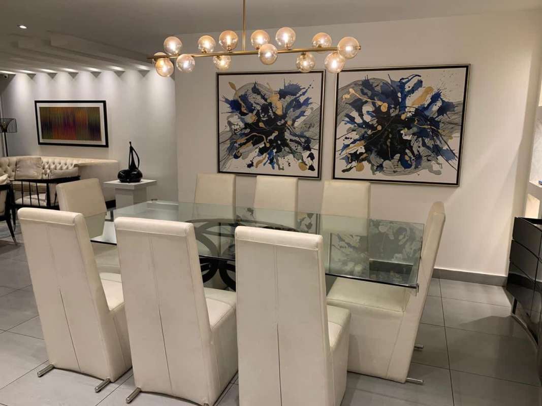 Modern dining area with glass table, white chairs, statement lighting Punta Pacifica apartment