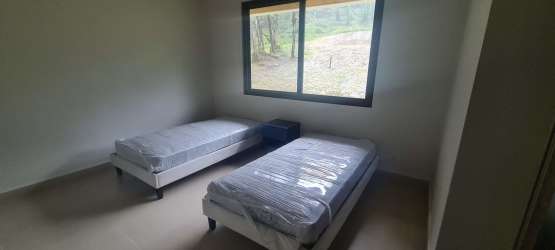 Minimalistic bedroom with two twin beds, large window, forest view at PH Valle Bonito Altos del María Panama