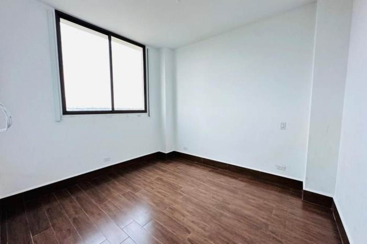 Bright bedroom with large window and wood-look tile at PH Costamare Costa Sur Panama