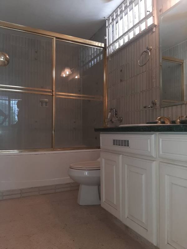 Bathroom with gold-trimmed glass shower enclosure, toilet and vanity in duplex Betania Panama