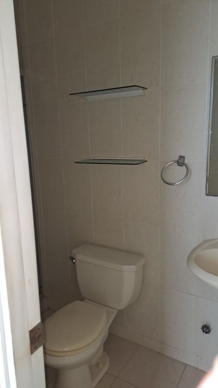 Compact bathroom with beige ceramic tiles, white toilet and sink in PH Majestic Gardens Panama City