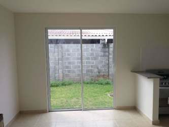 Spacious tiled living room with open kitchen and sliding glass door in La Arboleda house