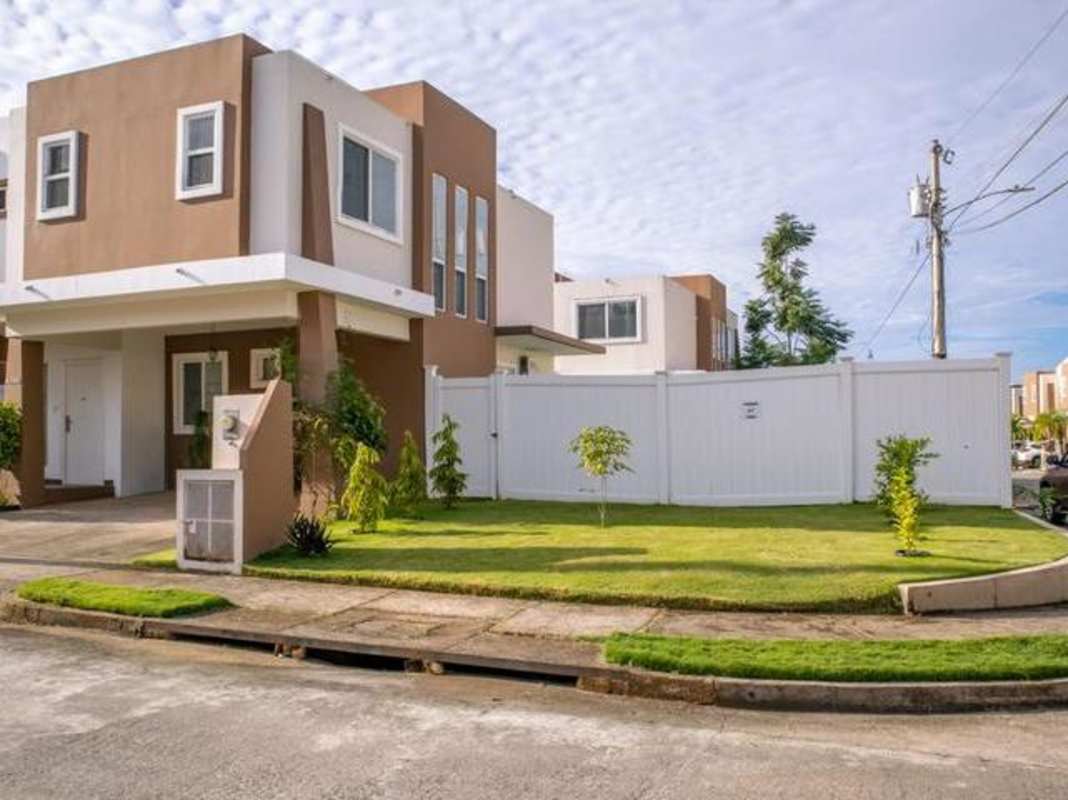 Fenced backyard with covered patio green lawn and two-story house PH Everest Brisas del Golf