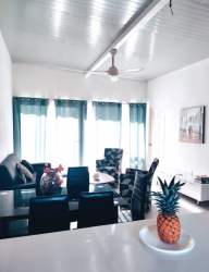 Bright open plan living dining area with colorful chairs, bar kitchen island and windows in coastal duplex