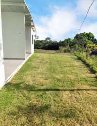Side exterior of white duplex with covered patio, fence, and large grassy yard near Pedasi beach